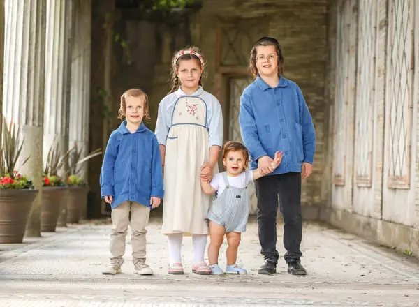 Four siblings in blue by a white barn, outdoor family photography by Photoholic, Rockland County NY